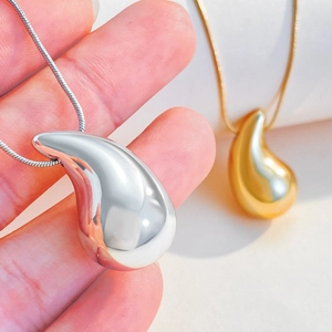 Close-up of polished silver and gold liquid teardrop pendants with elegant snake chains