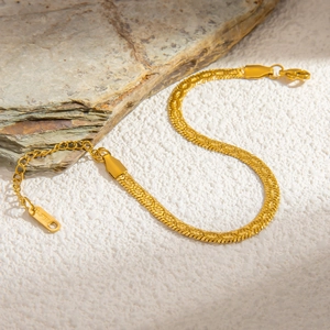 Detail view of 18K gold plated stainless steel snake chain bracelet on a stone texture
