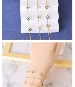 Detailed shot of gold plated bracelets with shell clover and blue evil eye charms