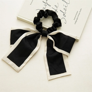 Detail of elegant black ribbon hair tie with white piping and long flowing streamers