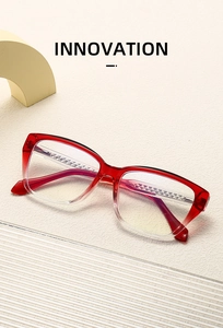 Detail view of red gradient eyewear frame with diamond textured temples on beige surface