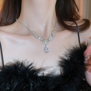 Close-up of silver water drop necklace with sparkling diamonds on female model