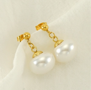 Détail de boucles d'oreilles vintage en perles dorées sur un élégant tissu blanc texturé