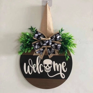 Detail of wooden Halloween Welcome sign with skull bow and decorative greenery