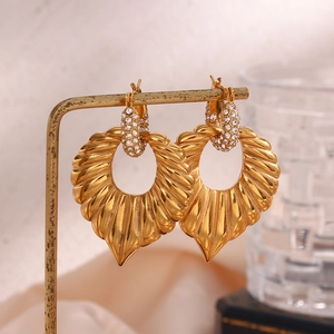 Macro view of vintage gold shell earrings with diamond-encrusted studs and textured metal