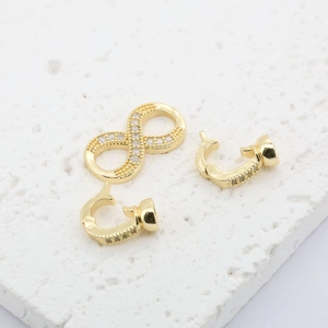 Macro view of gold 18K plated infinity symbol connector with micro-inlaid diamonds