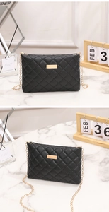 Detail of black quilted crossbody bag with gold chain strap and metal buckle