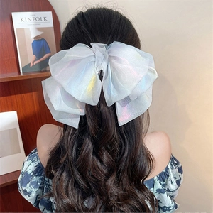 Detail of a large iridescent organza bow hair clip worn by a model in a cozy setting
