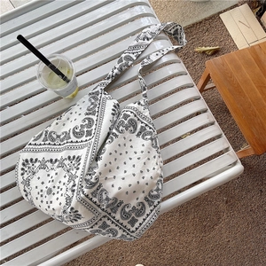 Retro black and white paisley canvas tote bag on a bench in natural outdoor light