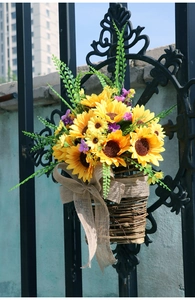 Dettaglio del cesto in vimini sospeso con girasoli e fiocco di iuta su recinzione nera