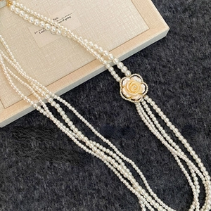 Elegant multi-strand pearl necklace featuring a diamond-encrusted camellia flower clasp