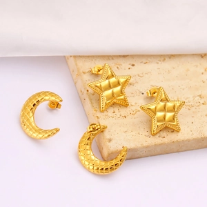 Macro detail of golden star and moon earrings featuring a textured quilted grid pattern