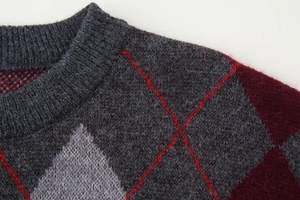 Detail of argyle pattern knit sweater with grey and burgundy wool texture and crew neck
