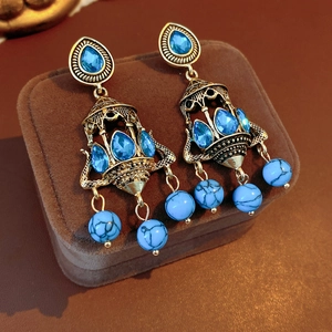 Detail of vintage chandelier earrings with blue stones on a luxury velvet jewelry box
