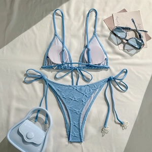 Detail of sky blue bikini with textured fabric and delicate white flower charms