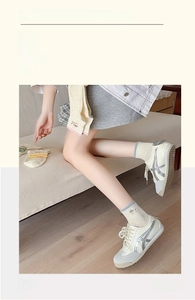 Close-up of cream knit ankle socks with cute cartoon bear embroidery and casual sneakers