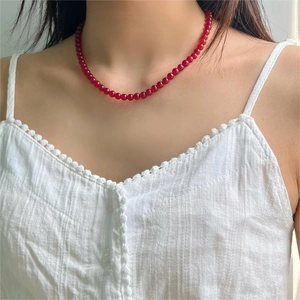 Detail of red agate bead necklace worn on neck with white summer outfit