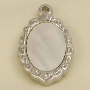 Macro shot of oval white mother of pearl pendant with silver embossed metal frame