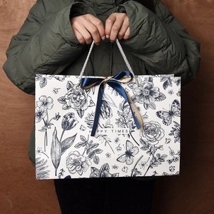 Elegant floral paper gift bag with blue ribbon handles and Happy Times message