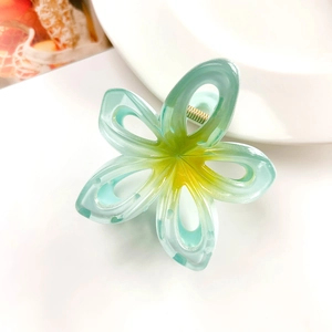 Detailed close-up of a hollow frangipani hair claw with mint green and yellow gradient finish
