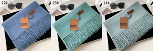 Detailed close-up of thick winter scarves with tassels in blue, green, and gray tones