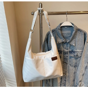Detail view of large white canvas tote bag showing double front pockets and adjustable strap