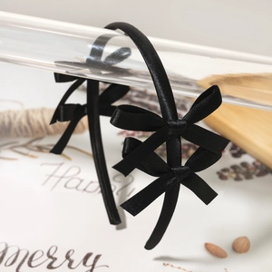 Detail of a black satin headband with double bows in elegant ballet style for kids