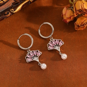 Détail de boucles d'oreilles feuille de ginkgo argentées avec pierres roses et perles