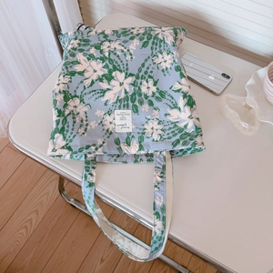 Detailed shot of floral canvas tote bag with stitched fabric label on a white table