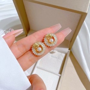 Detailed macro view of gold pearl earrings with baguette cubic zirconia and leaf accents