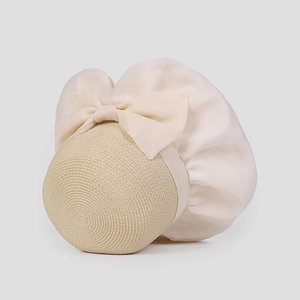 Dettaglio cappello di paglia elegante con maxi fiocco crema e mesh per protezione solare