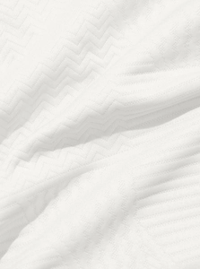 Detailed macro view of white heavy-knit fabric with a 3D zigzag herringbone texture