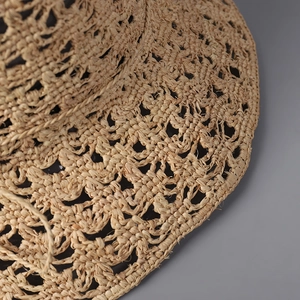 Détail d'un chapeau de soleil en raphia tressé main avec motifs au crochet ajourés