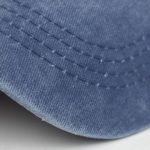 Close-up of reinforced stitching and distressed edge on cotton baseball cap brim