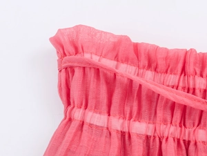 Detail of pink chiffon fabric with ruffled edges and elastic gathered smocking design