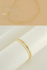 Detail of 18K gold-plated double-layer anklet with flat snake and bead chain texture