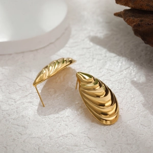 Detail view of 18k gold stainless steel earrings with textured shell pattern design
