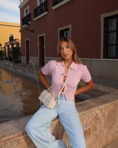 Close-up of pink short sleeve knit top with triple bow ties and ribbed texture detail