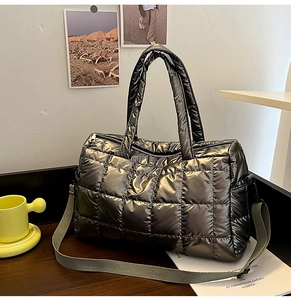 Detail of metallic grey quilted tote bag with top zipper on a wooden desktop