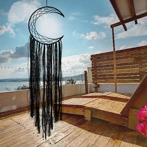 Detail of a black crescent moon dreamcatcher with lace tassels against a sea background