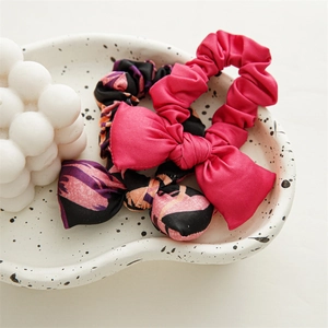 Silk bow scrunchies set in pink and floral black pattern on a decorative ceramic tray
