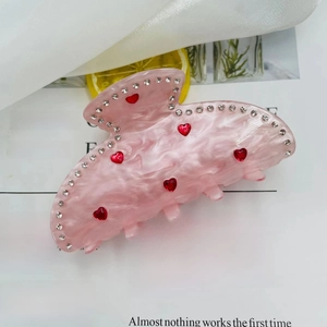 Detail view of pink marble acetate hair claw with red heart gems and sparkling rhinestones