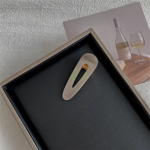 Detail of drop-shaped marble texture hair clip with elegant cutout design and gold hardware