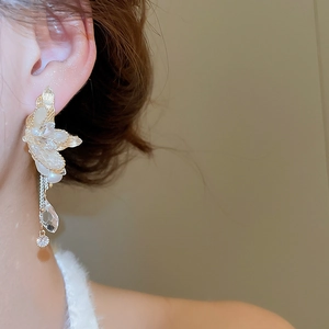 Detail of elegant gold flower earrings with pearls and long tassel crystals on a model
