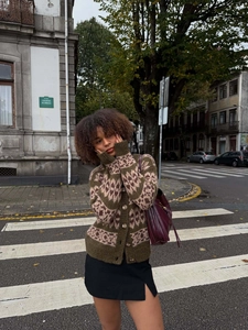 Close-up of vintage floral knit cardigan in dark green with stylish leather shoulder bag