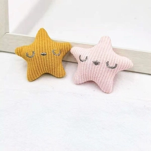 Detail of star-shaped plush pins in yellow and pink with embroidered faces