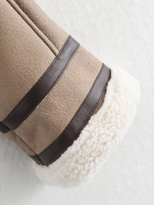 Detail of brown faux suede jacket sleeve with white shearling lining and leather trim