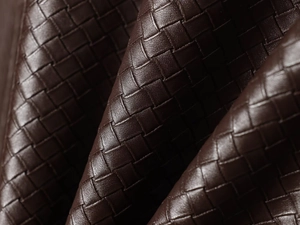 Macro view of dark brown woven faux leather jacket showing fine grain texture and detail