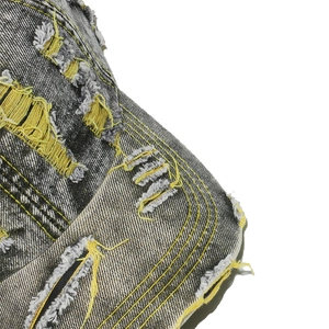 Détail d'une casquette en denim gris anthracite usé avec coutures jaunes et déchirures