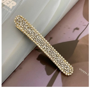 Close-up of golden rectangular hair clip with shimmering silver rhinestones detail